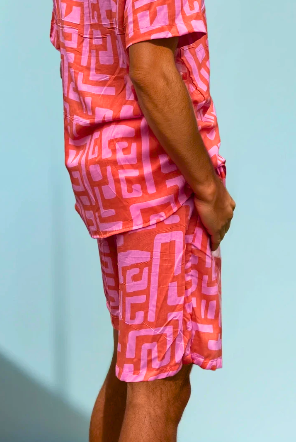 Model wearing the Hazy Maze Summer Punch Shorts in coral and pink maze print, standing in natural light.