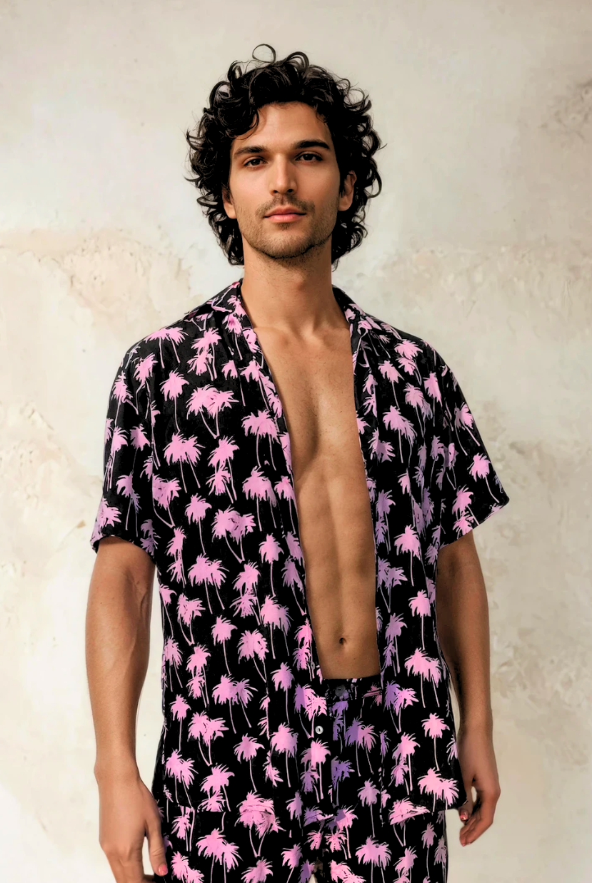 Model wearing the Malibu Barbie Palm Party short-sleeve rayon shirt in pink palm print, standing against a light textured wall.