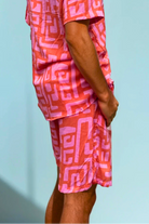 Model wearing the Hazy Maze Summer Punch Shorts in coral and pink maze print, standing in natural light.