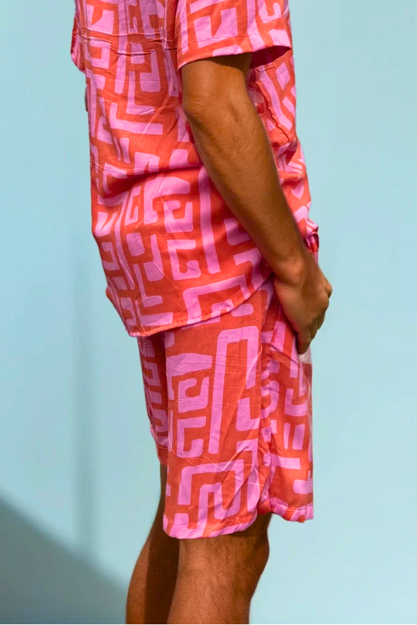 Model wearing the Hazy Maze Summer Punch Shorts in coral and pink maze print, standing in natural light.