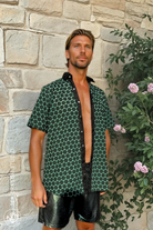 Front view of the Green and Pleasant Land shirt showing the green geometric print and linen placket, photographed outdoors.