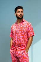 Model wearing the Hazy Maze Summer Punch Shirt in coral and pink maze print, standing in natural light.