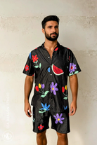 Model wearing the Midnight Picnic shirt and shorts set, side view showing floral-and-fruit print.