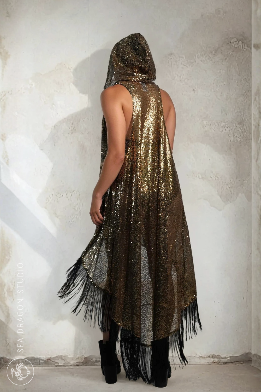 Back view of Sea Dragon Studio’s gold sequin kimono vest with hood and dramatic black fringe, shimmering in studio light.