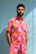 Model standing in a relaxed pose wearing Sea Dragon Studio’s Tropic Drift pink summer matching set against a sky-blue wall.
